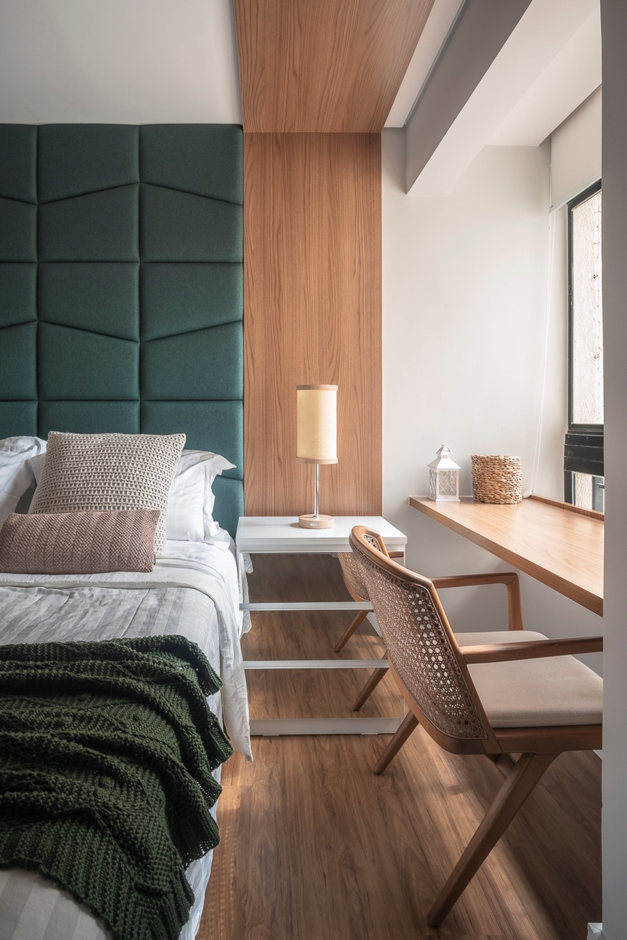 Quarto com cabeceira estofada verde e piso de madeira